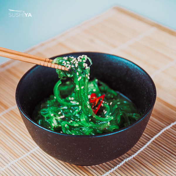 Na obrázku sa medzi paličkami v miske nachádza Wakame. Ide o zelenú dlhú morskú riasu