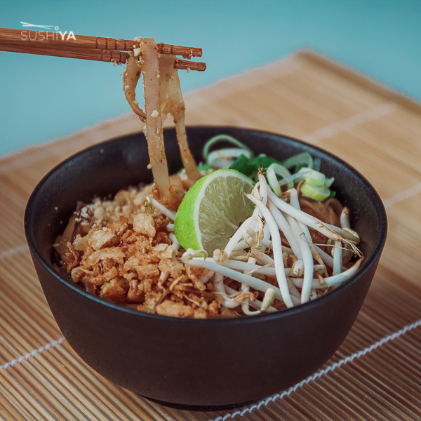 Na obrázku sa nachádza Pad thai. Ide o známe thajské jedlo s ryžovými rezancami, kuracím mäsom doplnené o krevety a arašidy.